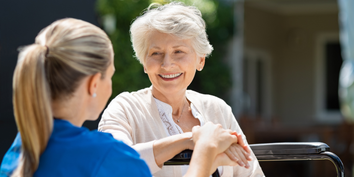 Senior woman smiling and talking with a caregiver, representing long-term care planning in retirement.